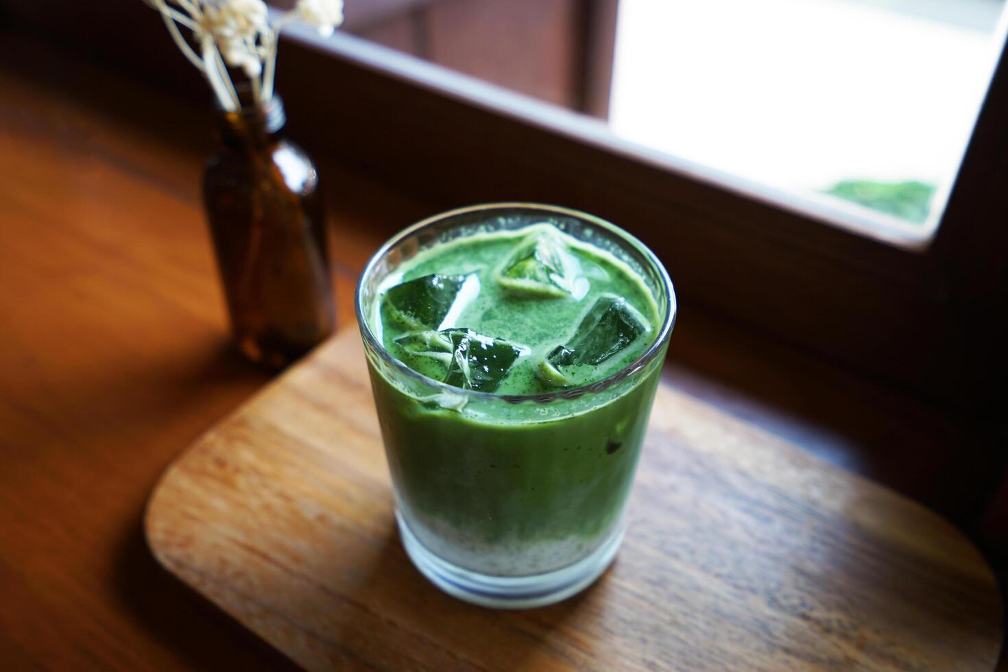 Close up glass of iced Matcha green tea with milk on wooden tray table photo