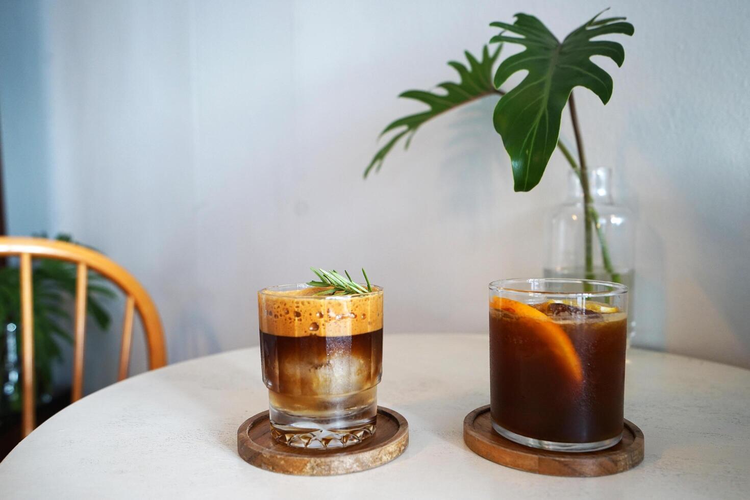Glasses of iced black coffee with slice of orange on wooden tray table photo