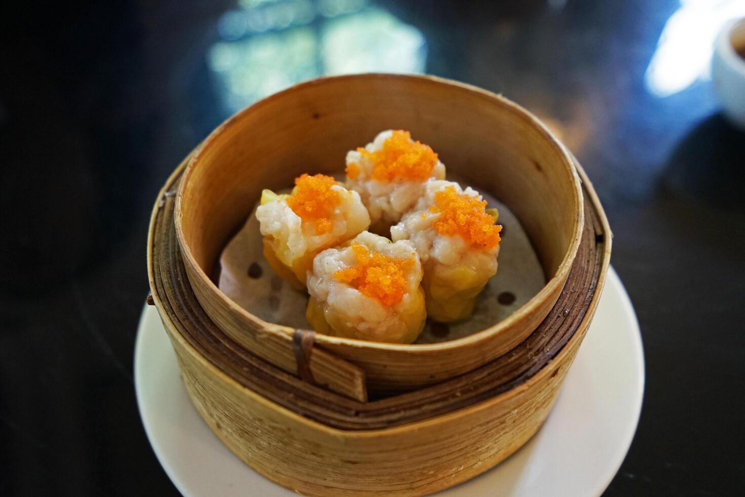 Close up Pork and Shrimp Shumai Dim Sum, Chinese dumplings served in steamed wooden basket container photo