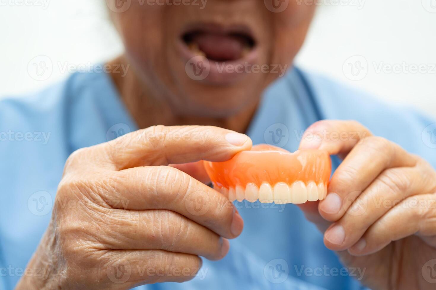 Asian elderly woman patient holding to use denture, photo