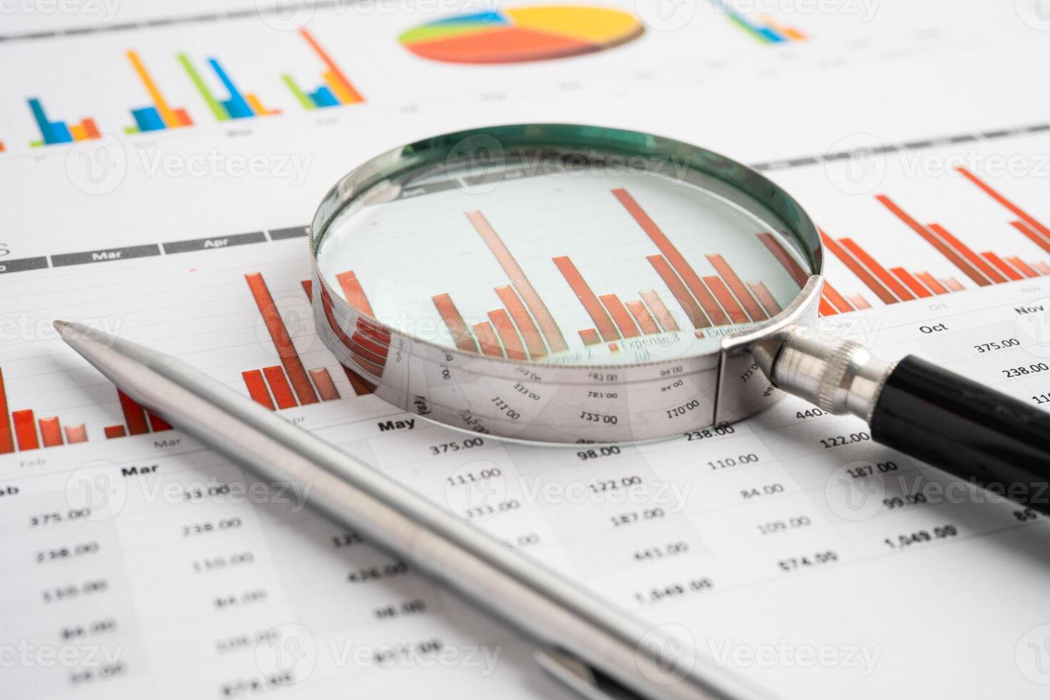 Magnifying glass on spreadsheet and graph paper. photo