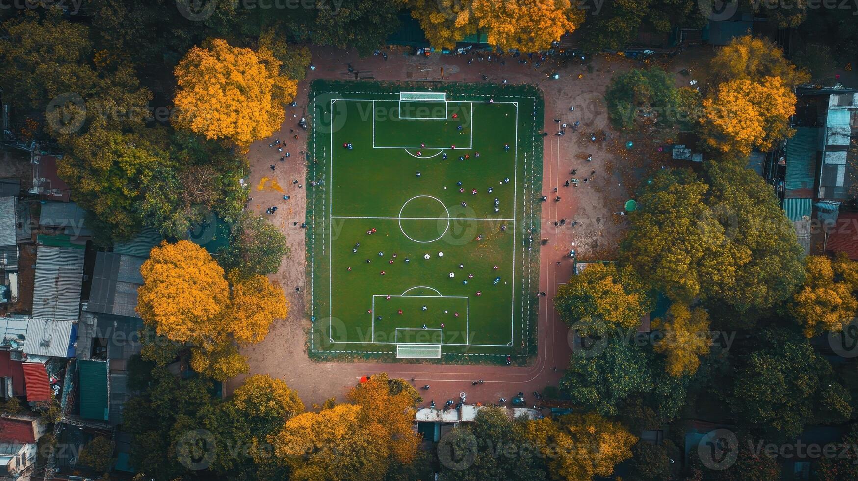 Aerial view of a vibrant soccer field surrounded by autumn trees and people playing. photo