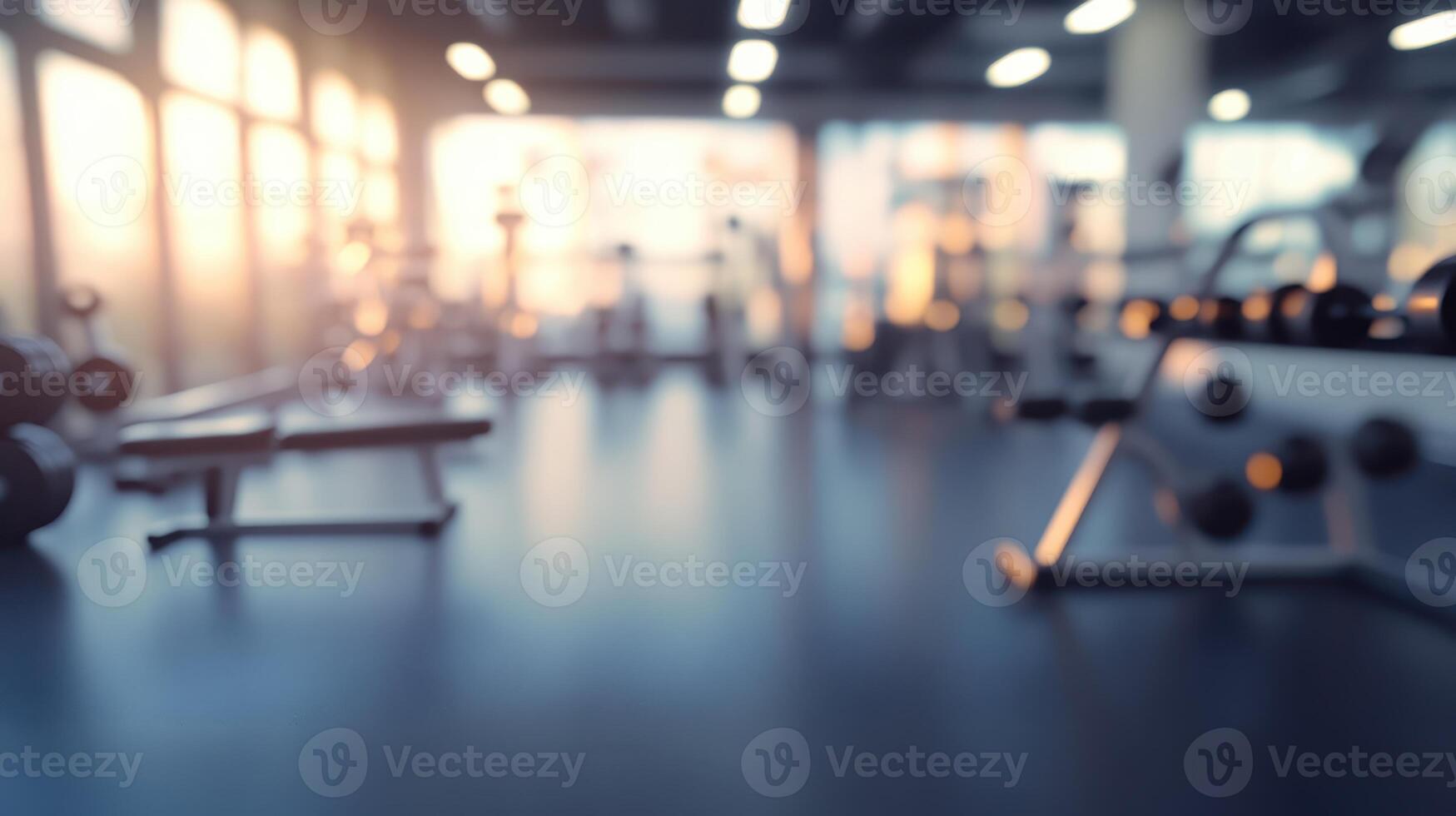 A blurred image of a gym interior with workout equipment and natural light. photo