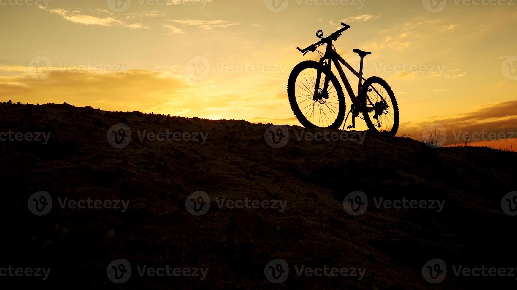 Silhouette of a Mountain Bike on a Hill at Sunset with Vibrant Sky and Dramatic Clouds in the Background photo