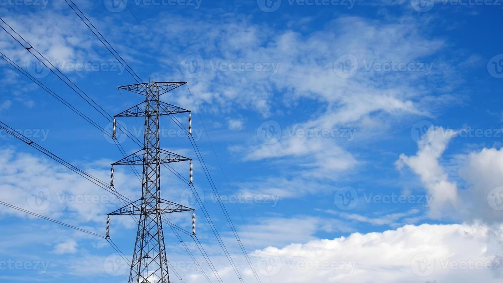 High Voltage Power Lines Against a Vibrant Blue Sky with Fluffy White Clouds on a Clear Day photo