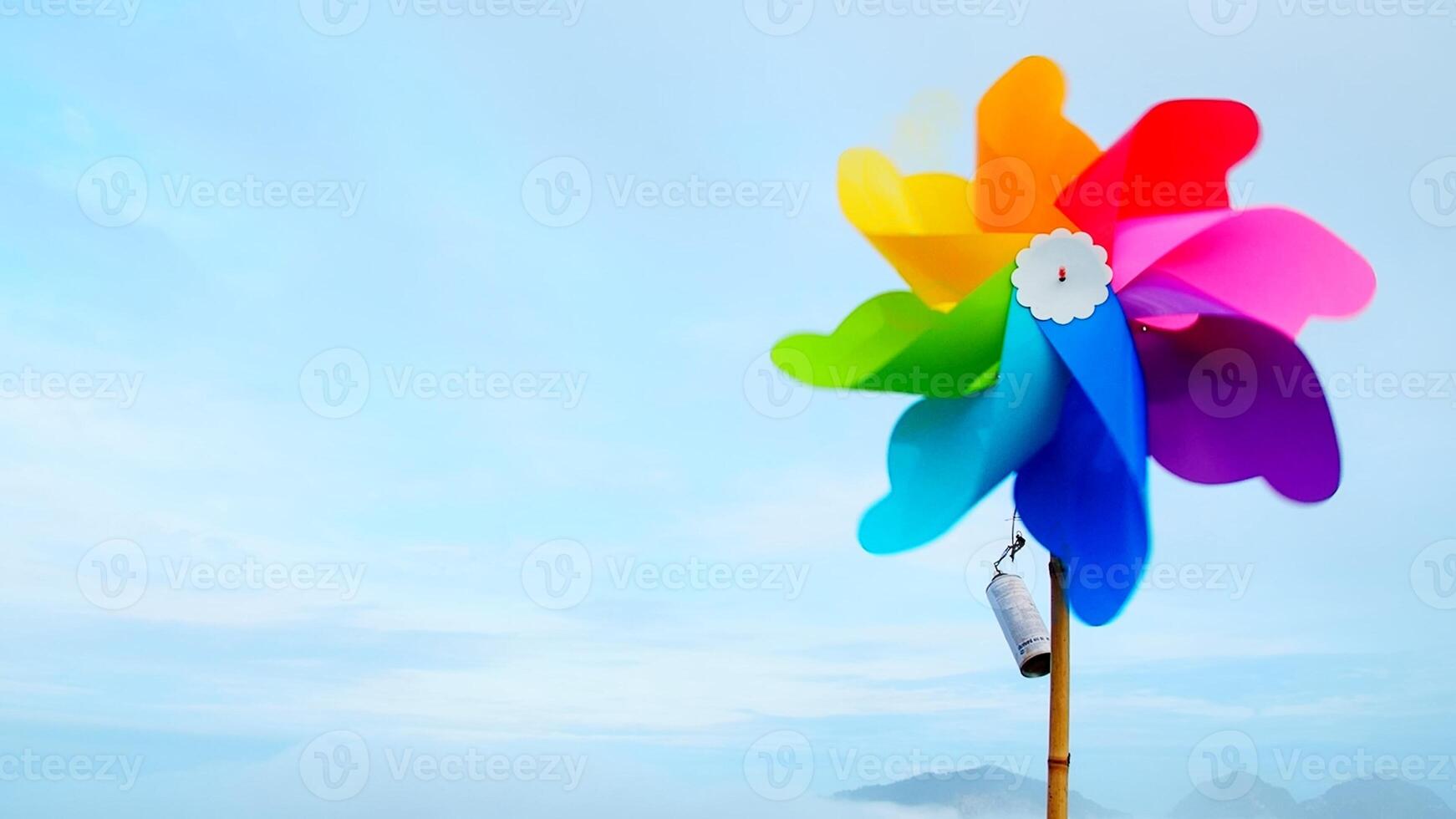 Colorful Pinwheel Against Clear Blue Sky with Mountains in Background on a Bright Sunny Day photo