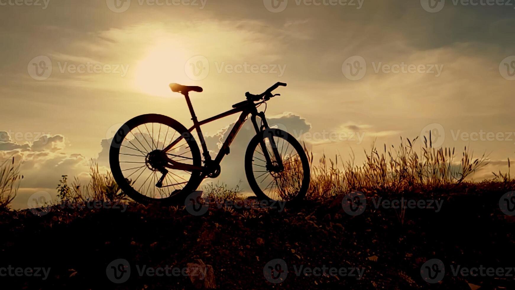 Silhouette of a Bicycle Against a Stunning Sunset Sky with Dramatic Clouds and Golden Light photo