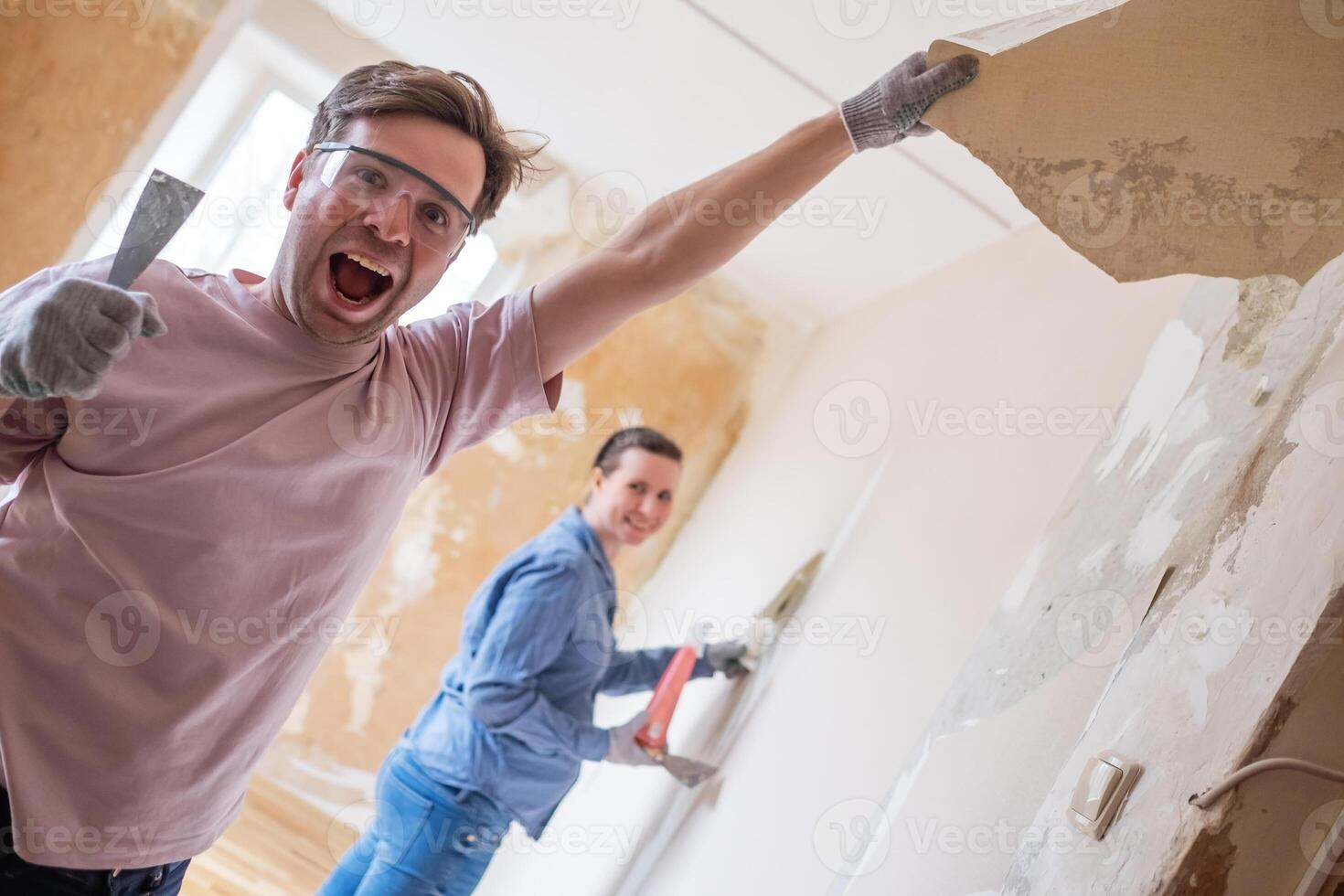 Young man removing old wallpaper from walls preparing for flat renovation. photo