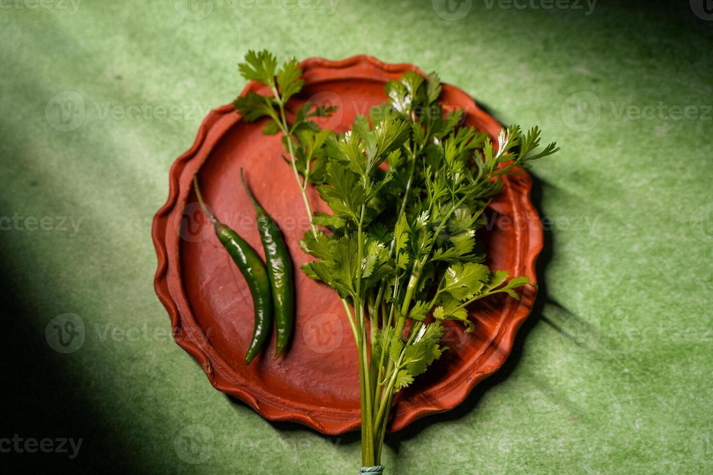 Coriander leaves and green chilies are kept in an earthen pot. photo