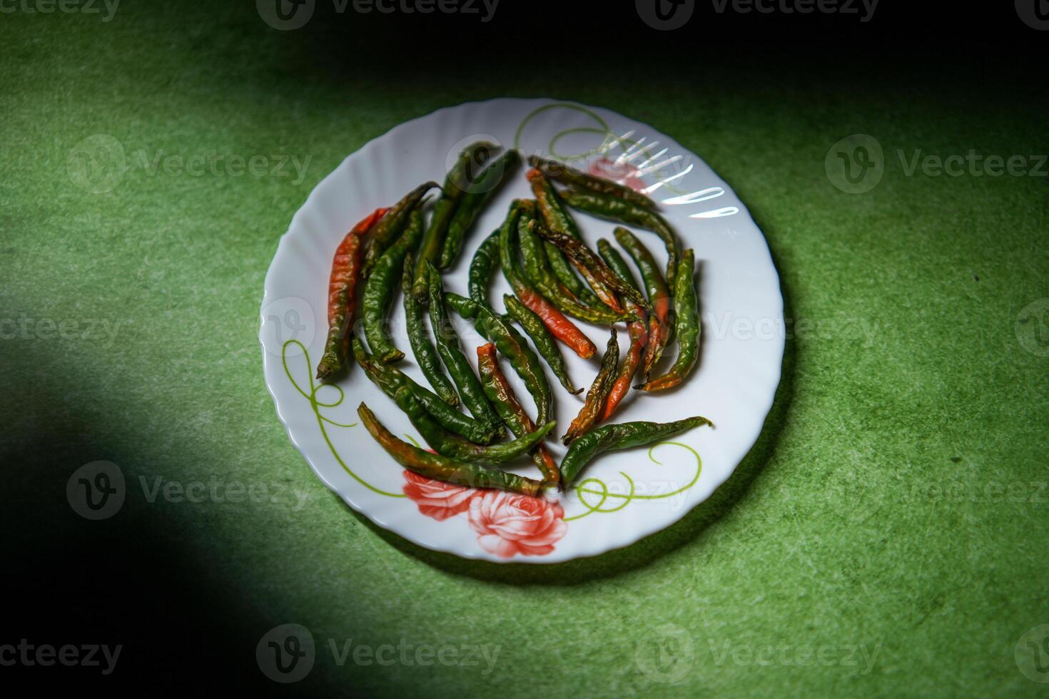 Half a dried green chili is placed on a plate. photo
