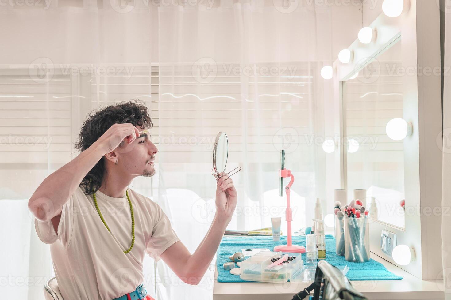 Young man applying makeup in front of mirror with led lights photo
