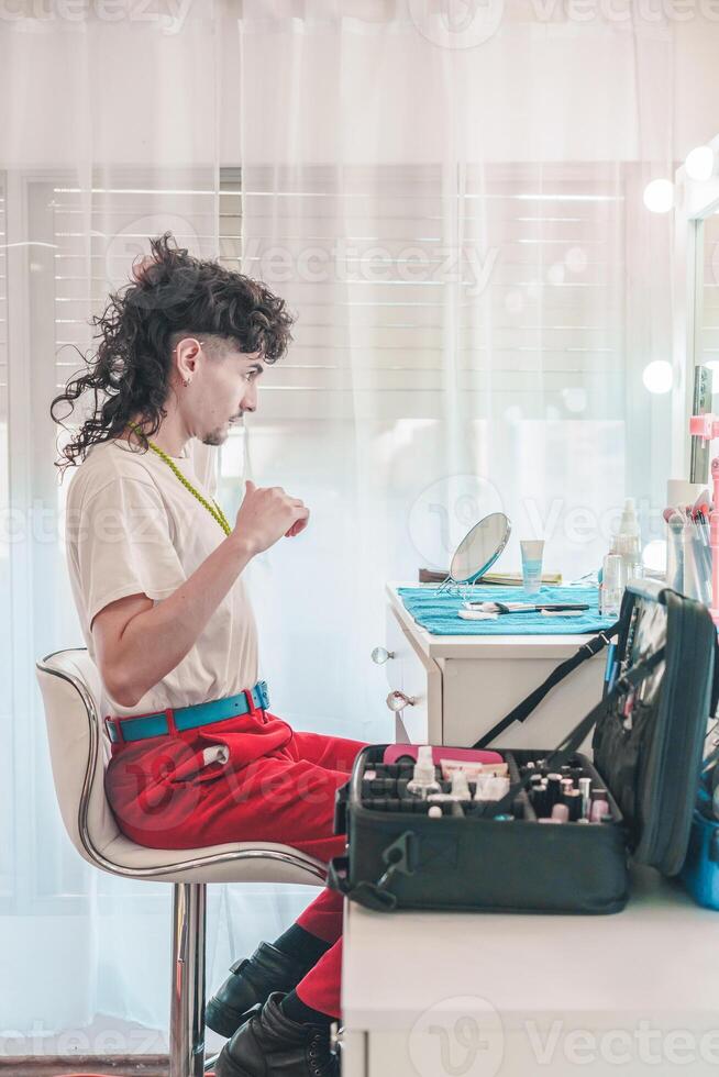 Young non-binary make-up artist combing hair and preparing for work at home photo