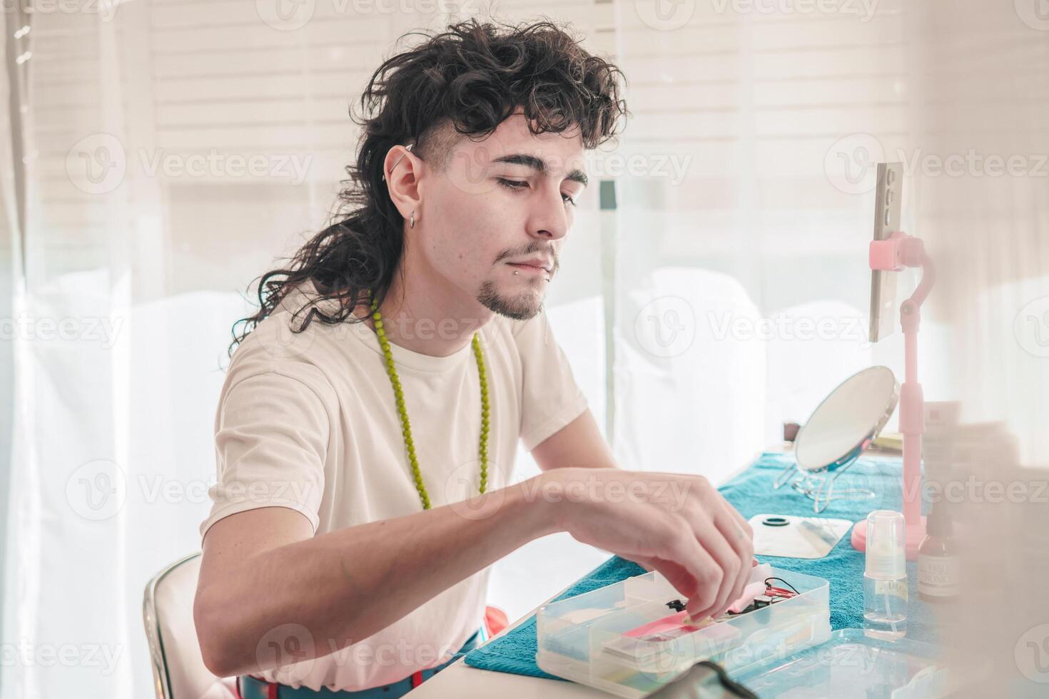 Young latin man applying makeup in front of mirror getting ready to go out photo