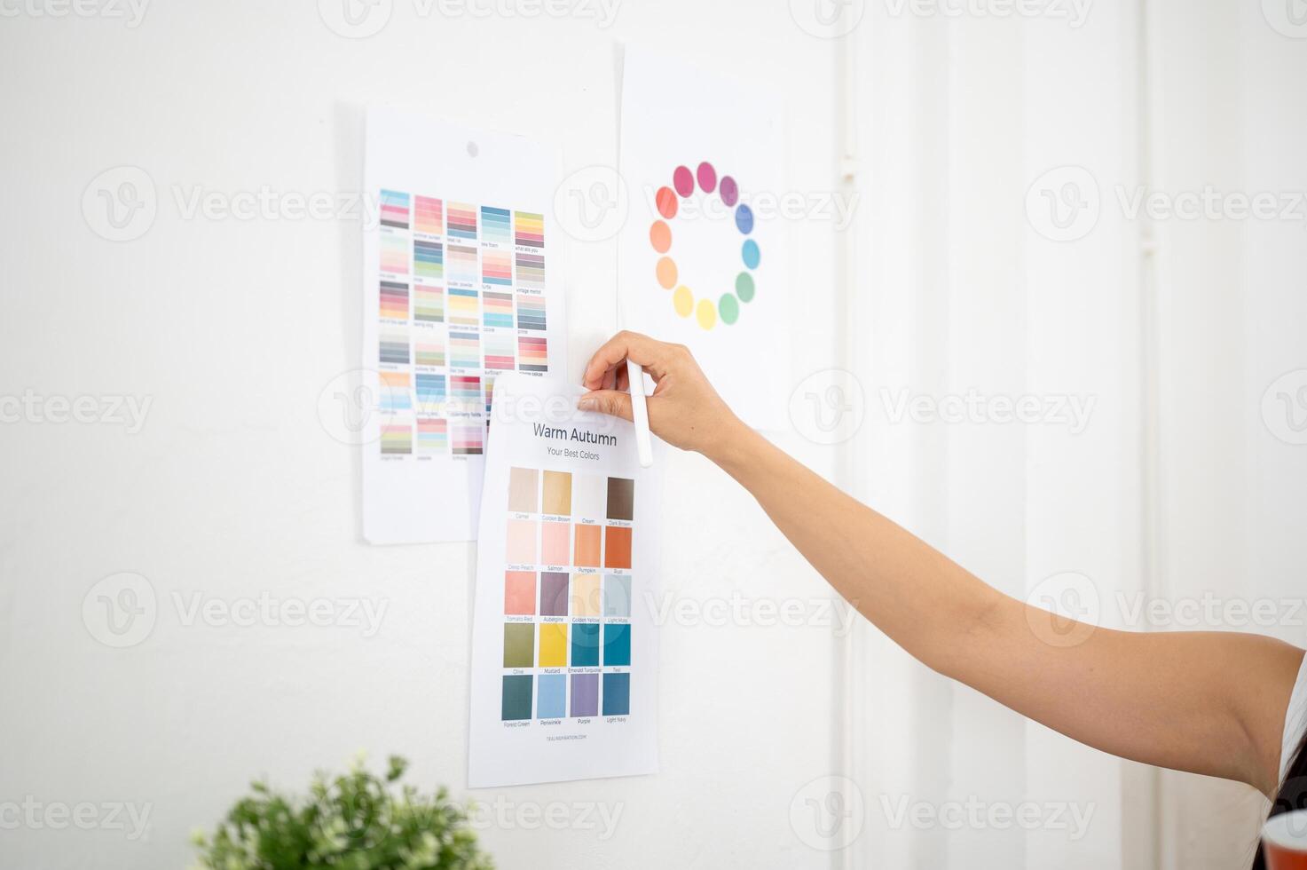 Close up of a hand sticking or taking off a printed color palette on the wall, Designer in office. photo