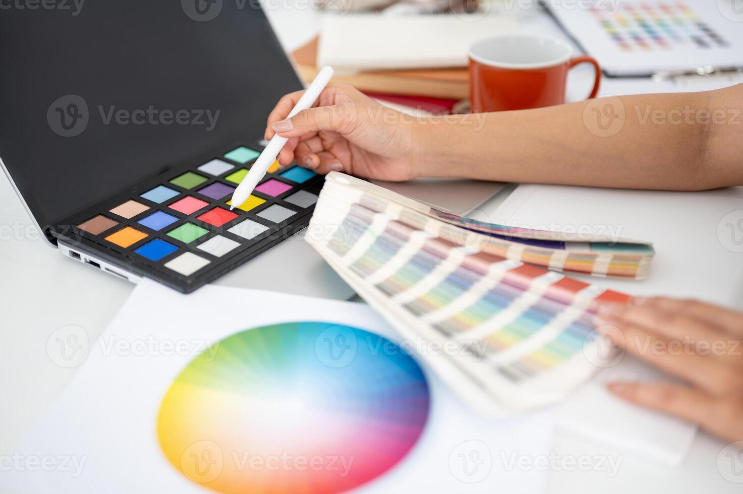 Close up of a hand pointing a stylus at red color on a color palette. Choosing or picking a color. photo