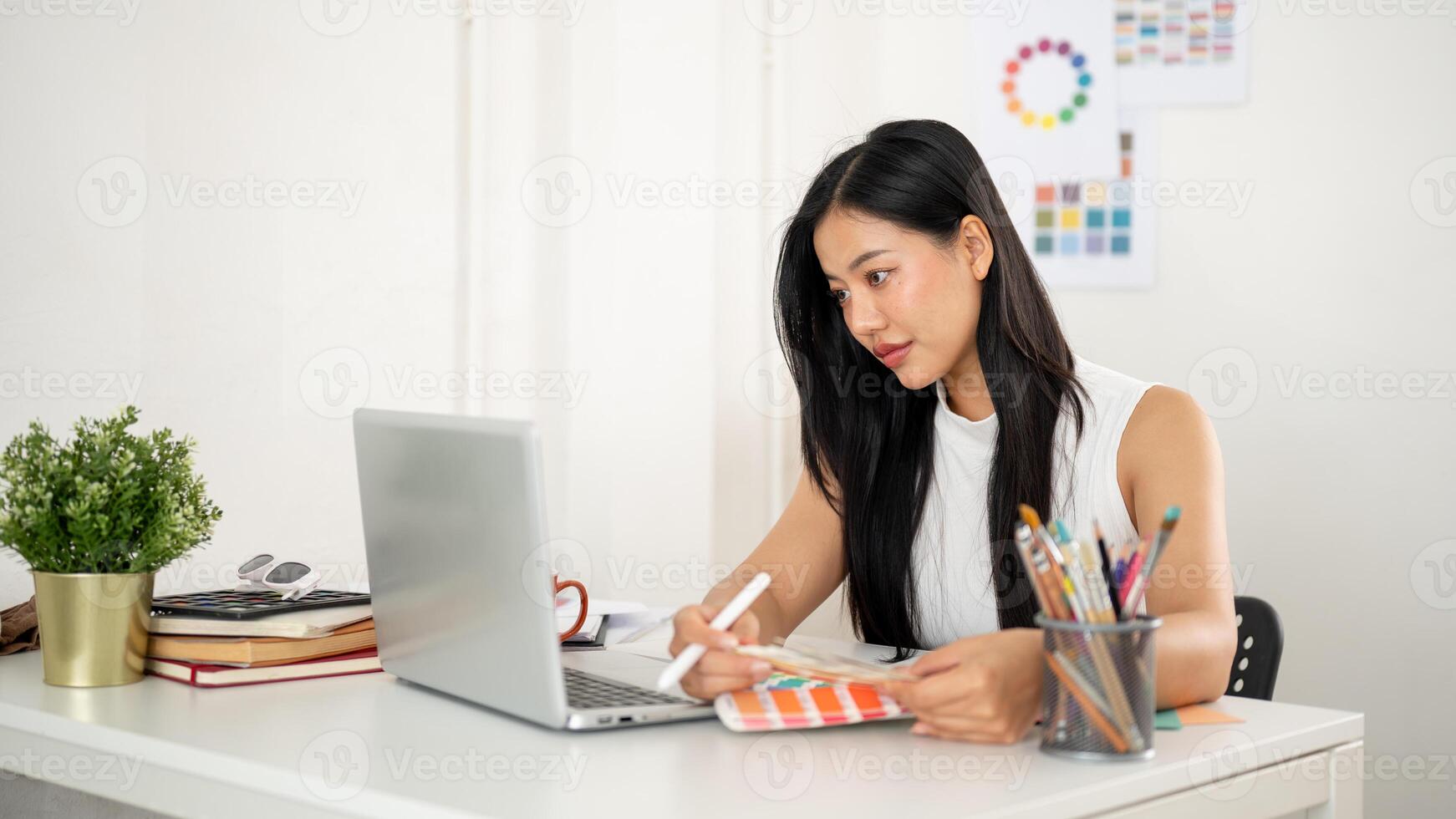 A woman is choosing the color from color charts or color palettes while looking at the laptop screen photo