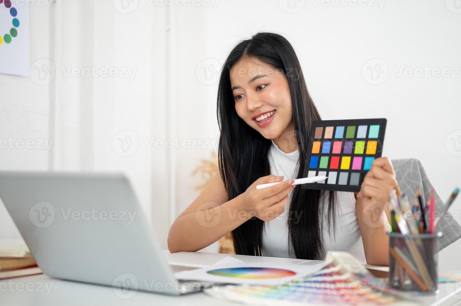 Asian woman is looking excited while showing color palette to a client or coworker in online meeting photo
