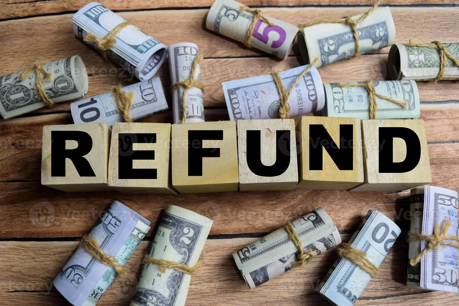 Concept word Refund on wooden blocks on a wooden table with dollar bills photo
