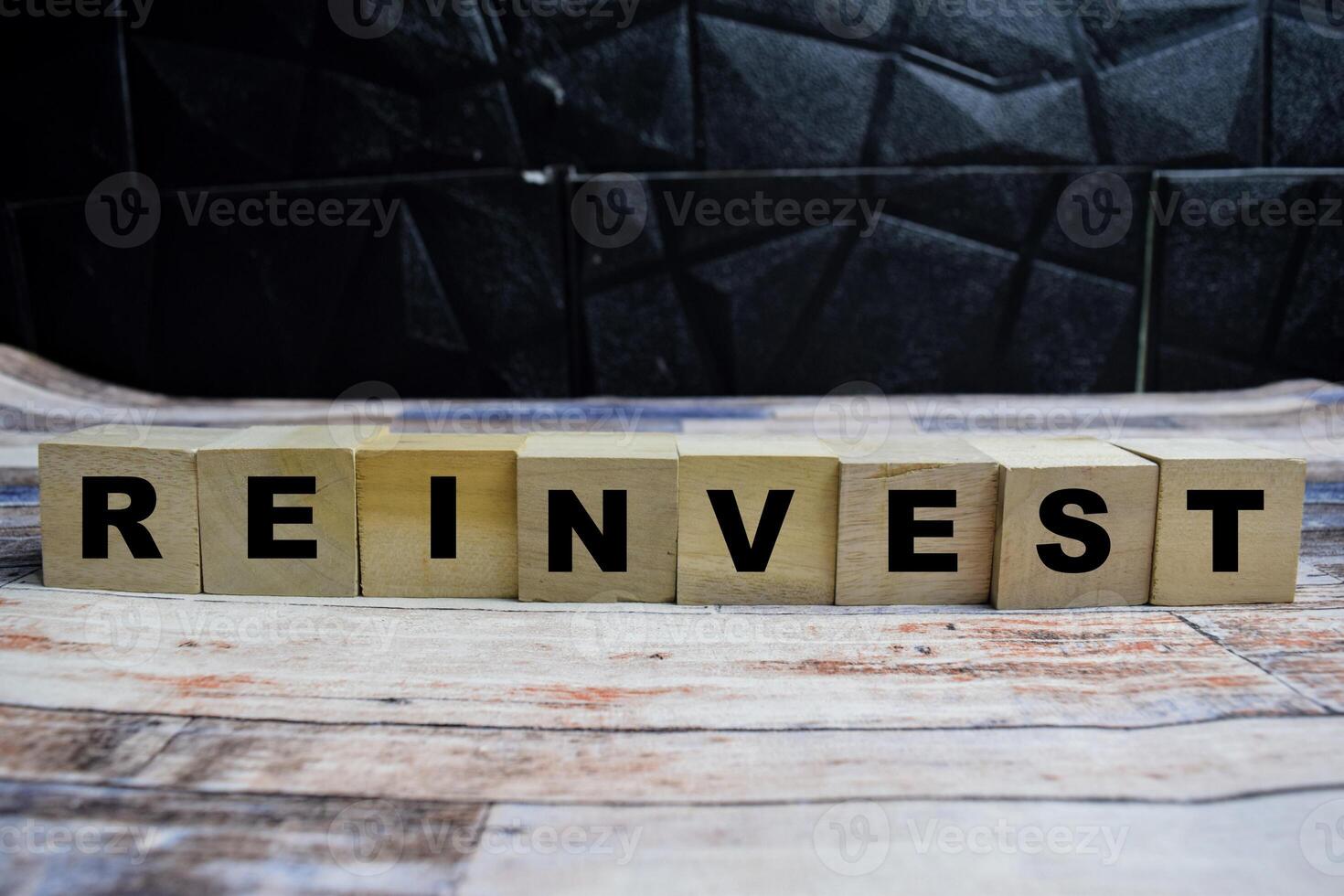Concept word Reinvest on wooden blocks on a wooden table photo