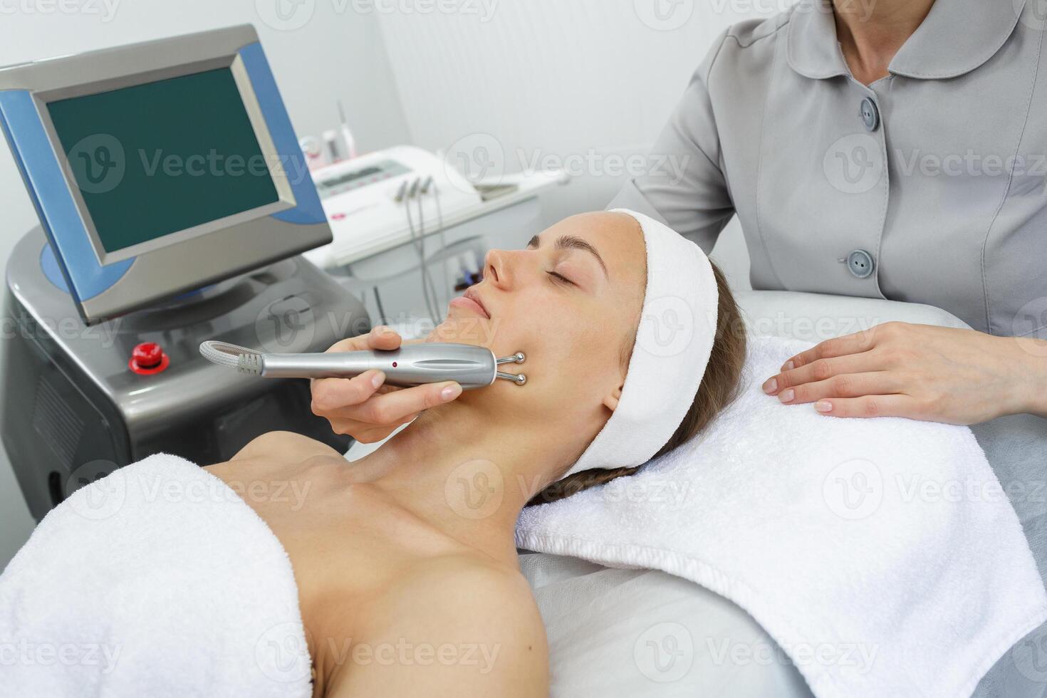 Facial skin tightening treatment using microcurrent device in professional beauty salon. photo