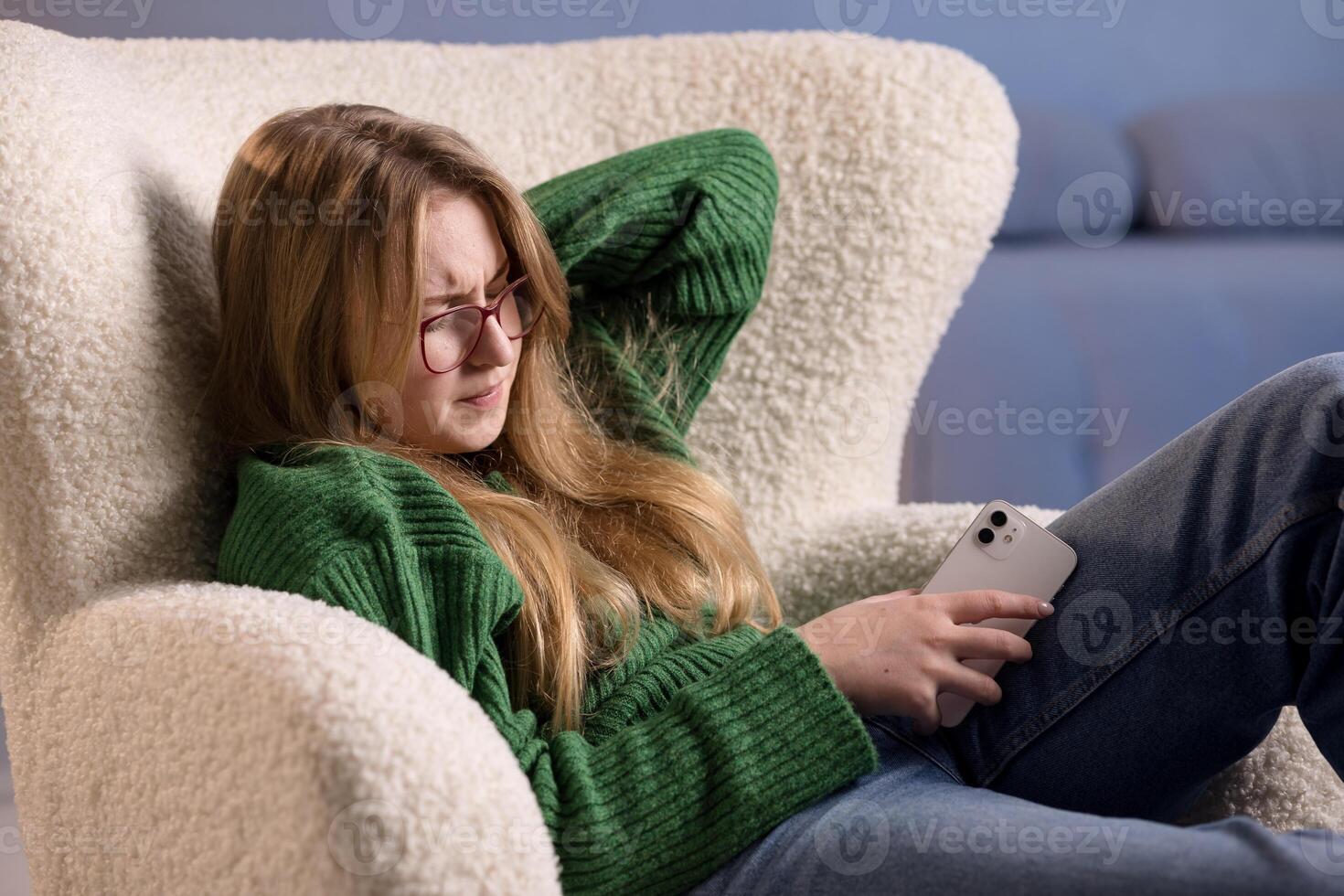 Woman holds phone and squints in pain, experiencing screen-related neck strain or eye fatigue. photo