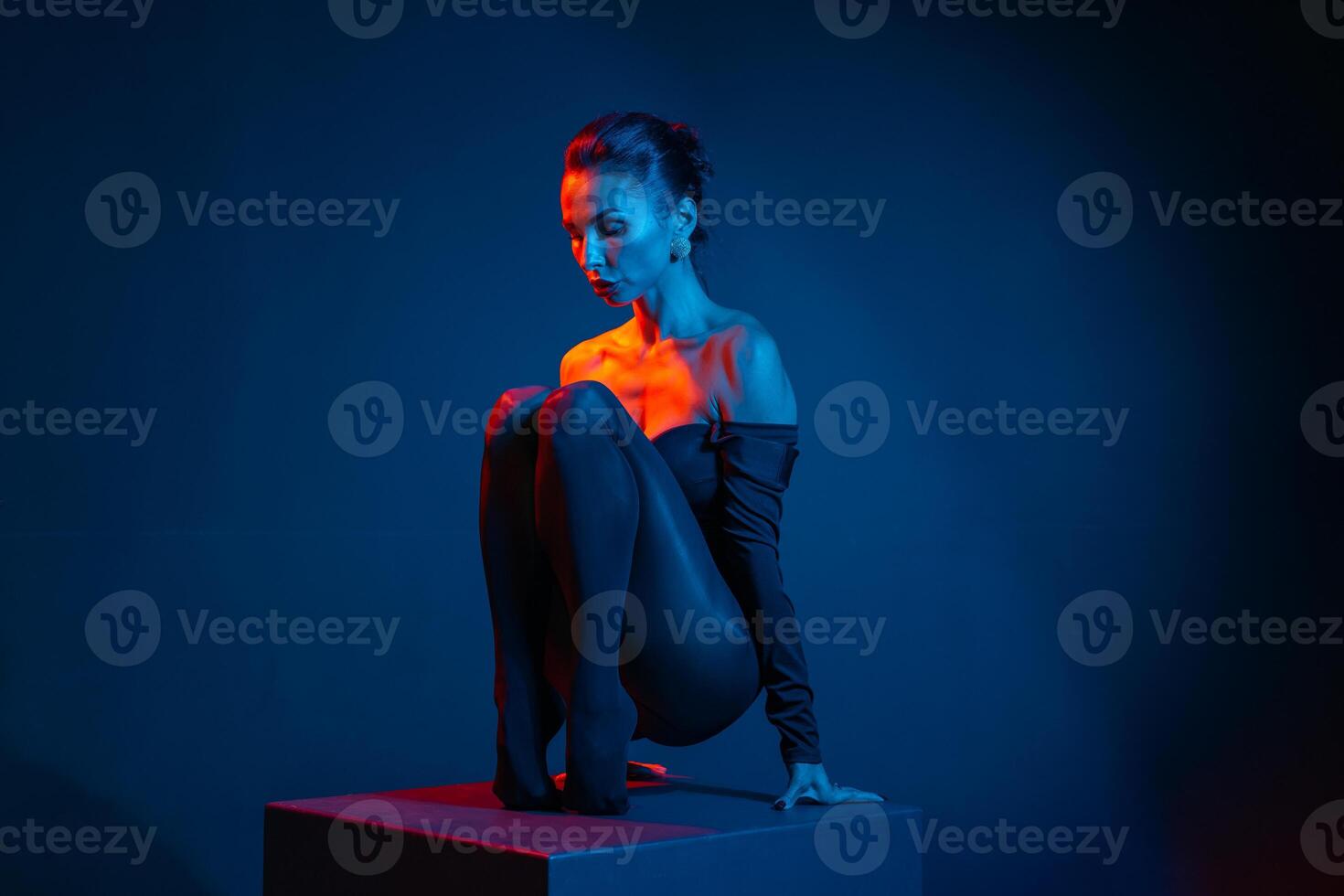 Stylized portrait of a woman posing in dramatic light, seated with expressive emotion. photo