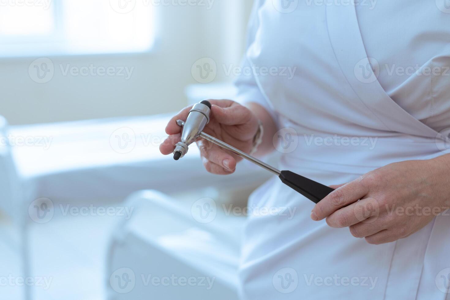 Close-up of a doctor holding a reflex hammer in a hospital room before a neurological check. photo