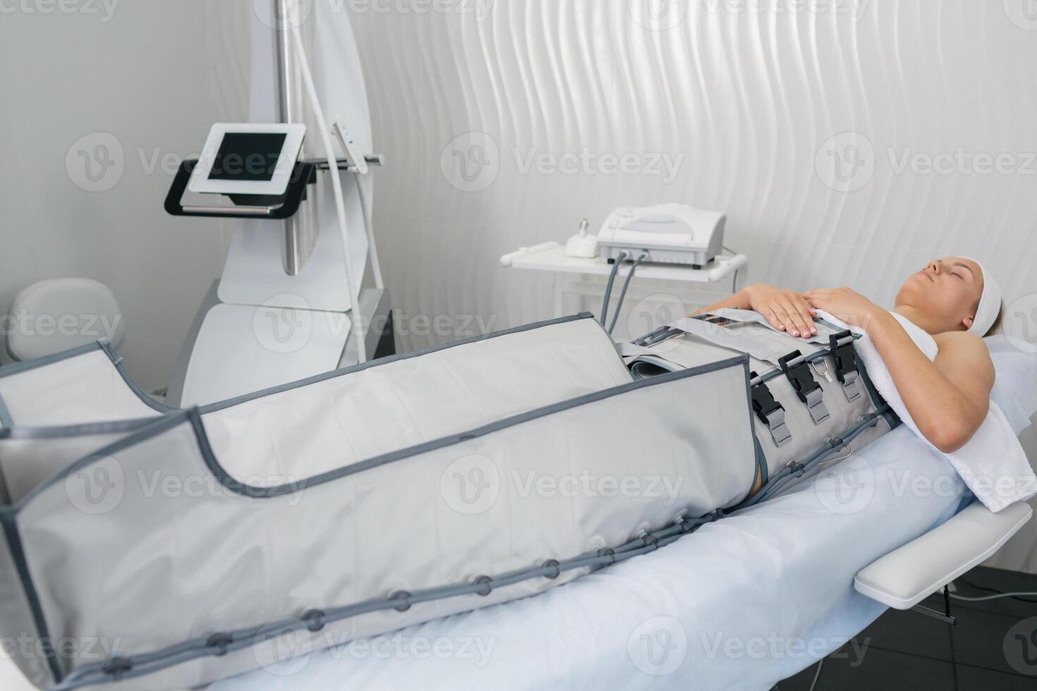 Female receiving compression therapy in spa center using professional pressotherapy equipment. photo