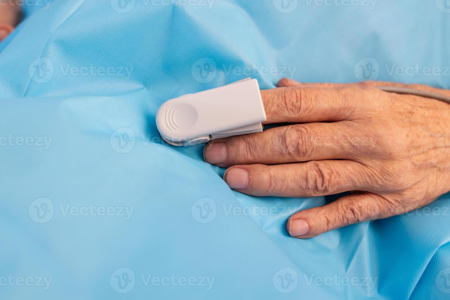 Elderly hand with pulse oximeter clip on finger for oxygen monitoring in medical setting. photo