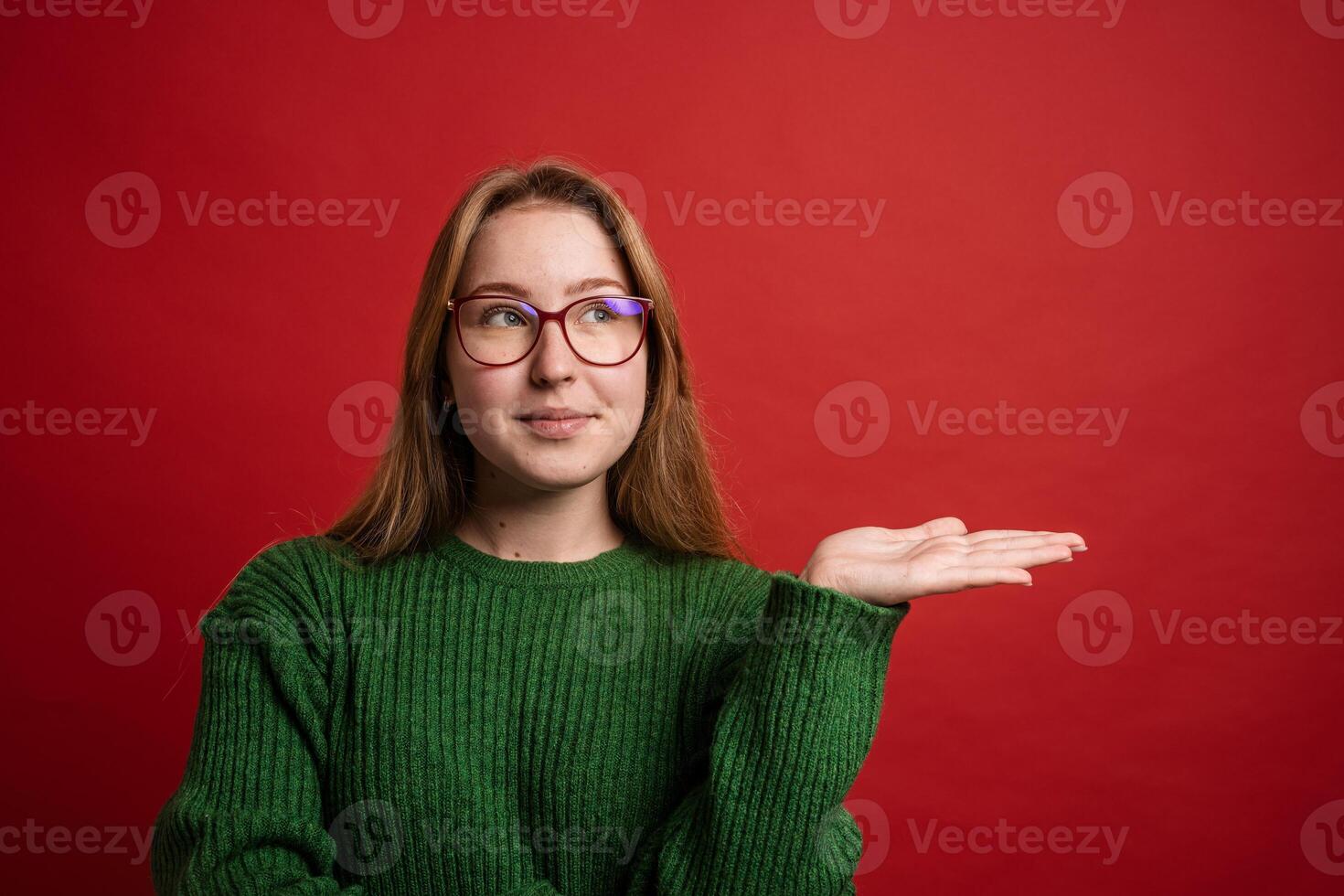 Happy woman showing open palm for product placement or message space on red background. photo