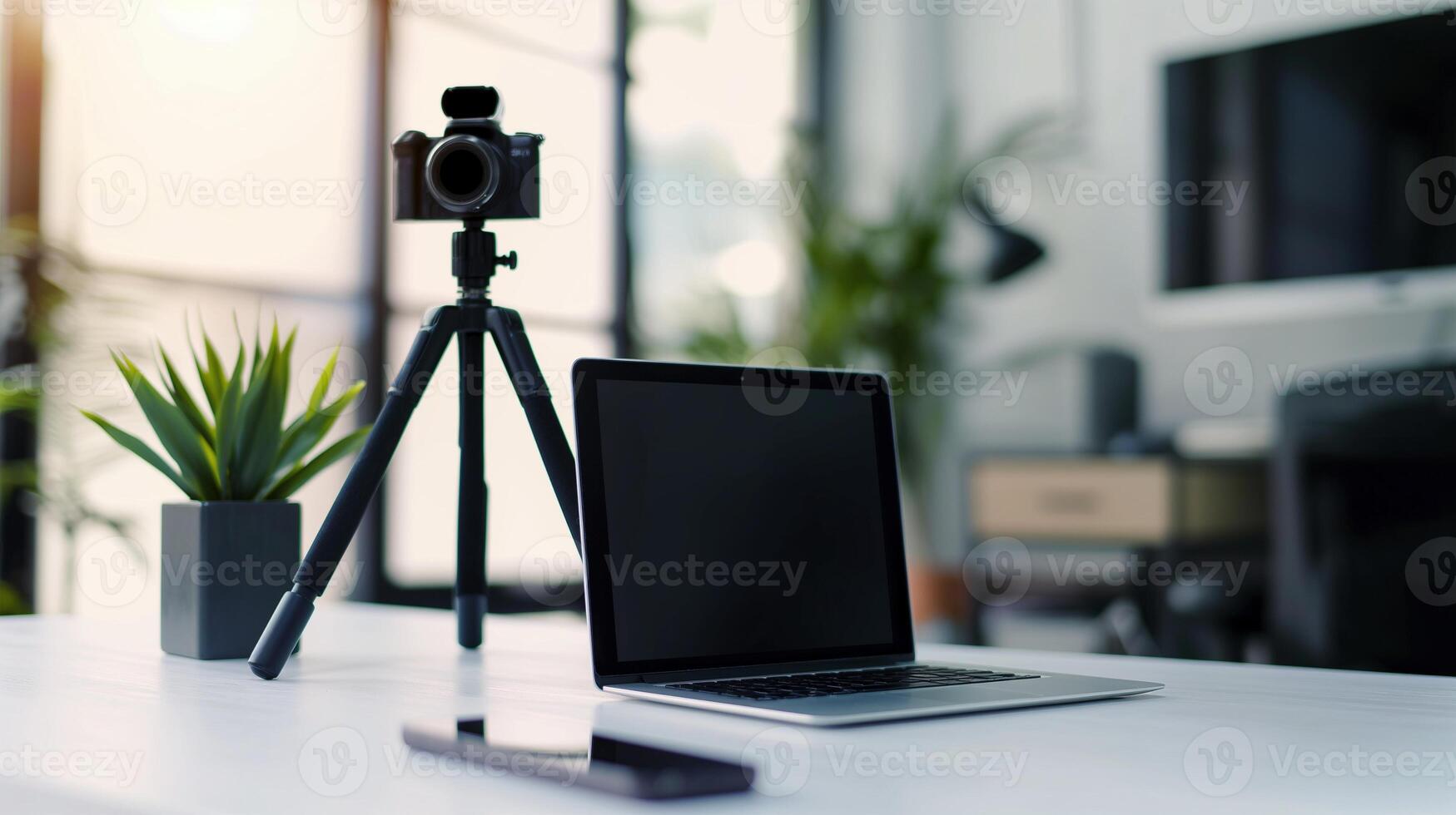 Modern workspace with laptop mockup and camera on tripod. White desk with natural light, green plants, notebook template advertising image. Mock up branding product, marketing material photo