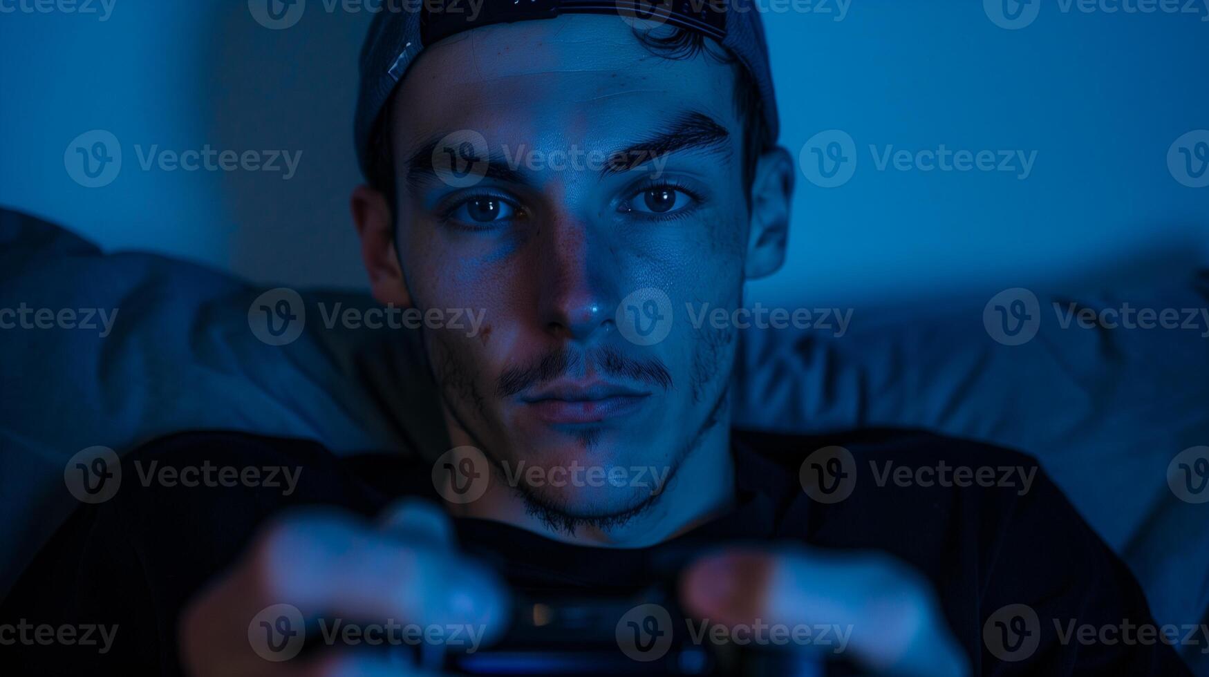 Focused gamer in blue light playing console at night image closeup. Caucasian man wearing cap holding game controller close-up photography. Immersive gaming concept photo realistic