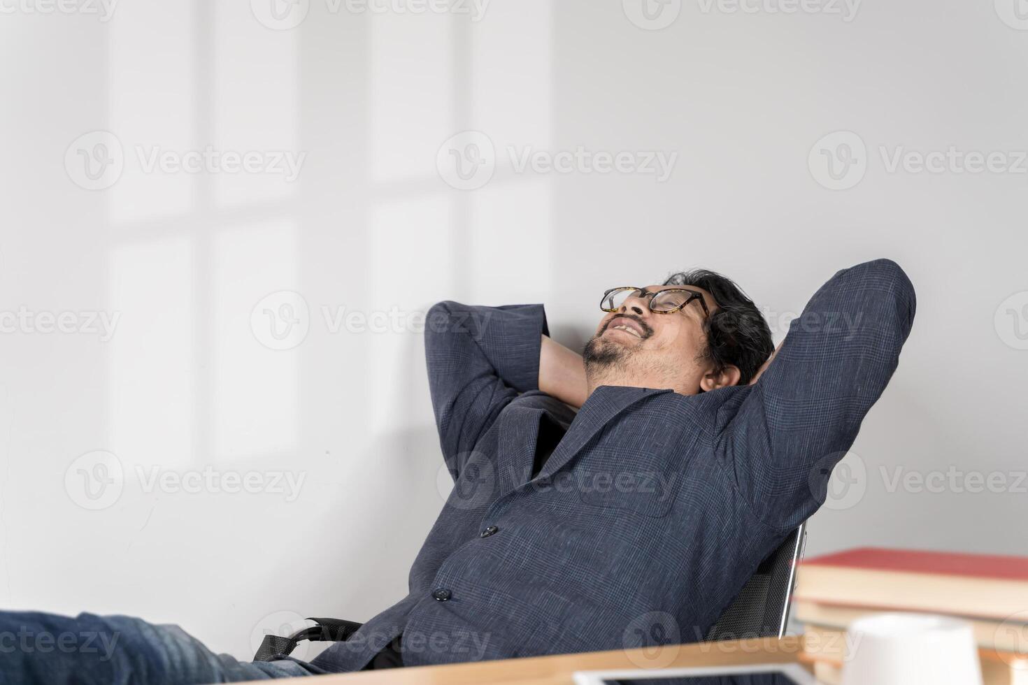 Calm millennial man in glasses sit relax at home office workplace take nap or daydream. photo