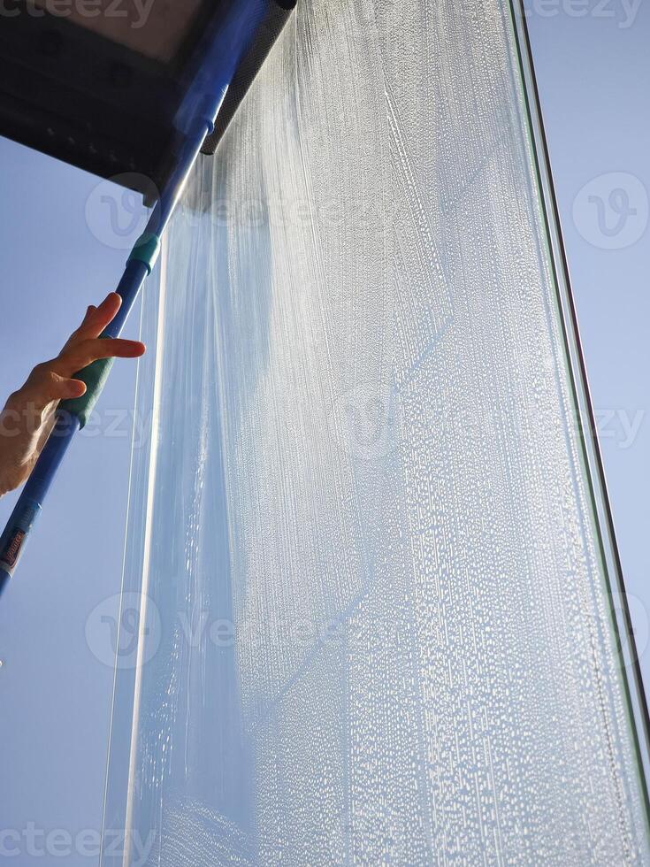 Window cleaner using squeegee cleaning glass panel on building exterior photo