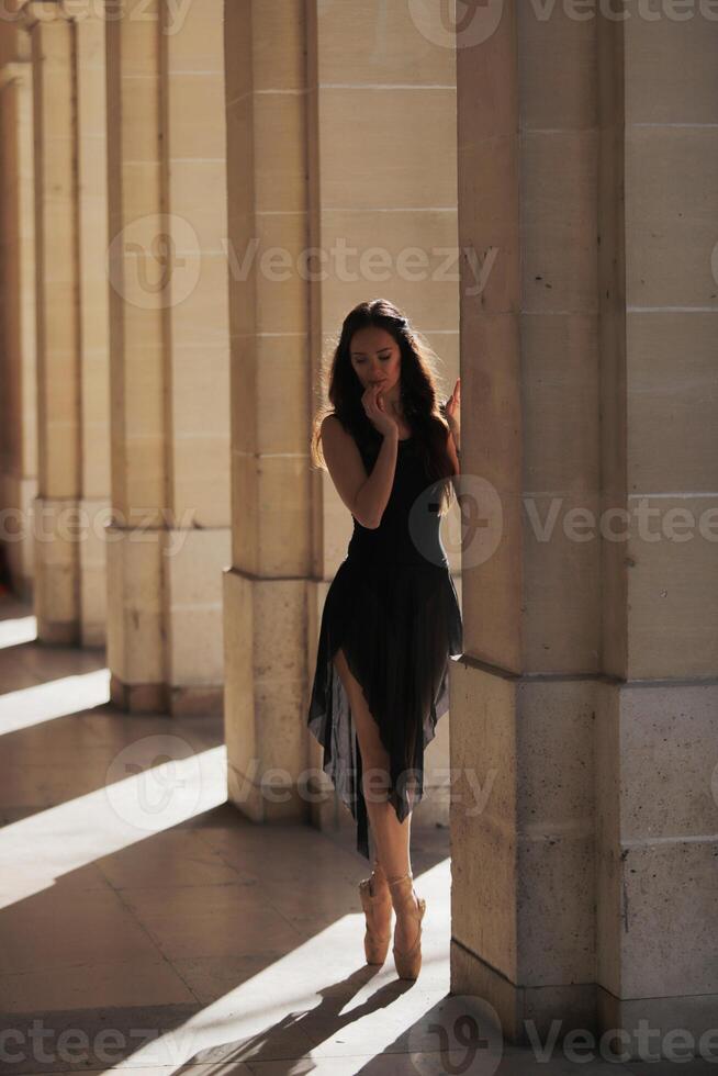 Graceful ballerina standing en pointe in quiet corridor with soft natural light photo