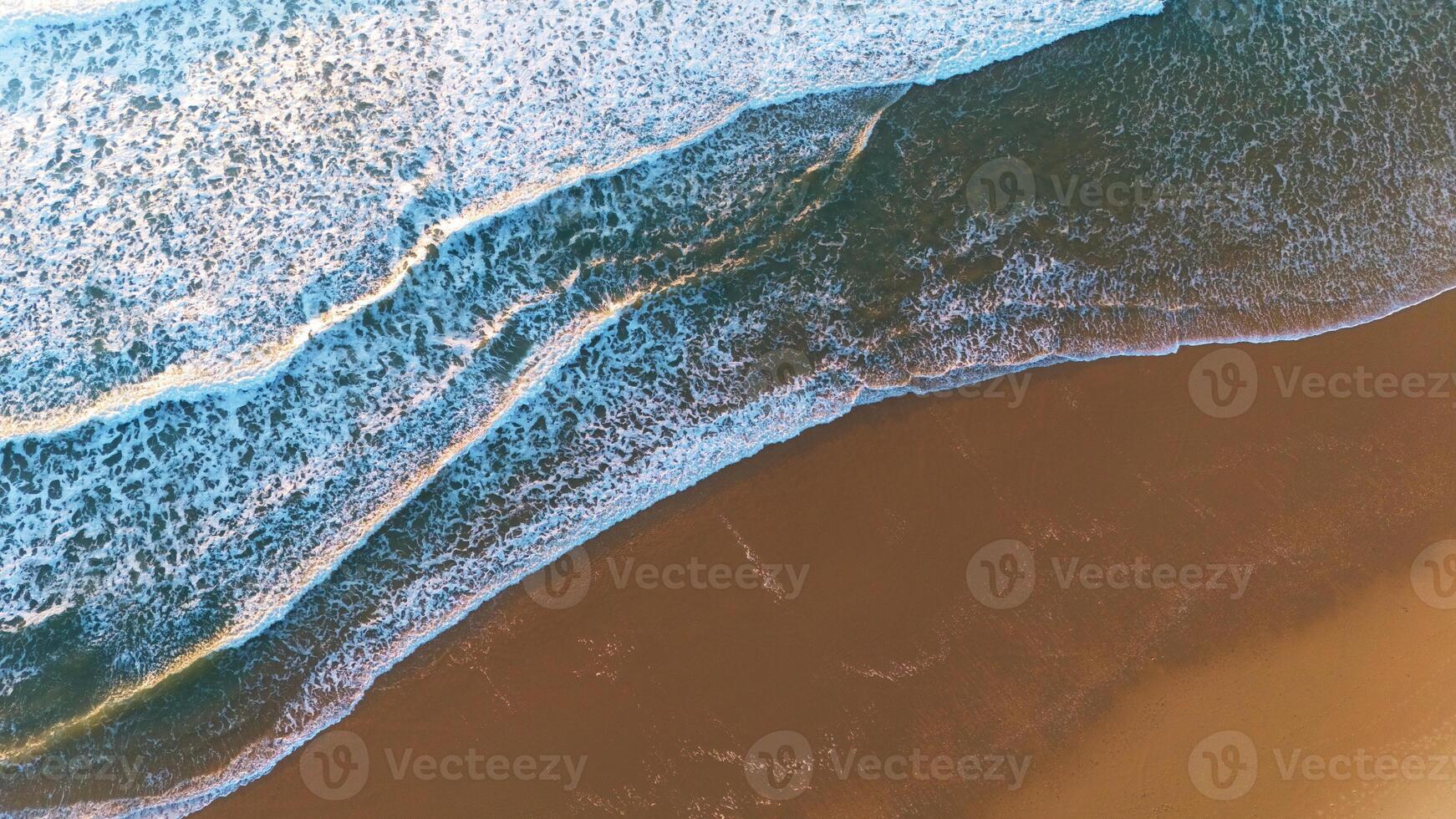 Top-Down Drone Shot of Waves Breaking on Smooth Sandy Shore photo
