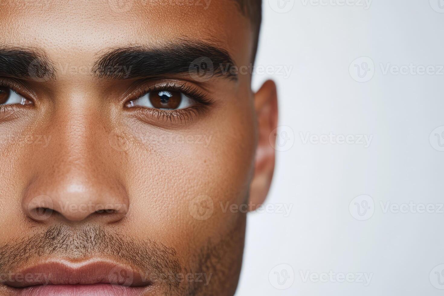 A handsome man with dark features showcases his expressive eyes and defined facial structure against a soft, neutral background photo