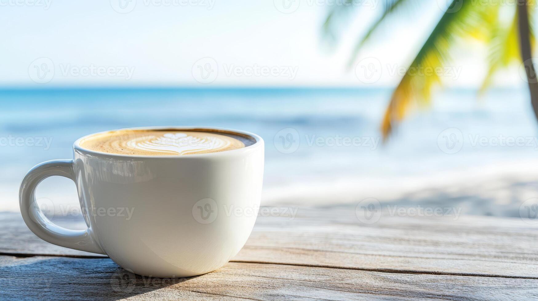 A white mug filled with coffee showcases intricate latte art on a wooden table by the beach. The serene ocean and palm trees create a relaxing atmosphere photo