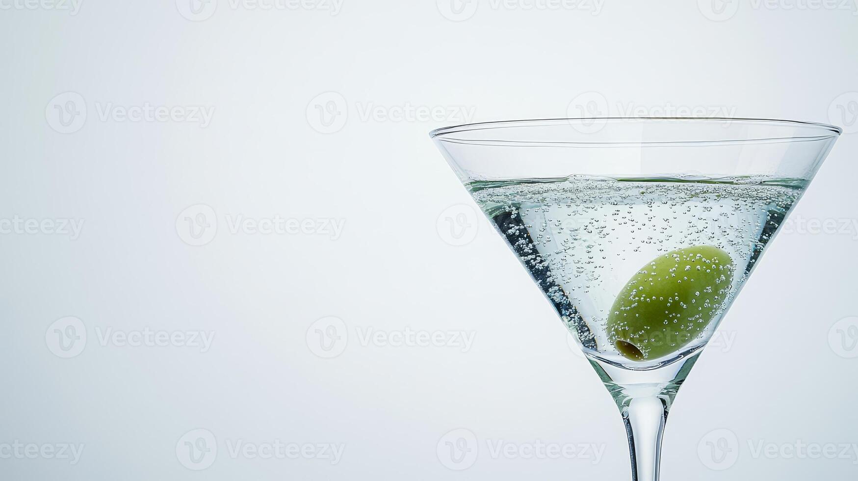 An extreme close-up captures an olive resting at the bottom of a martini glass filled with effervescent liquid, showcasing bubbles rising around it photo