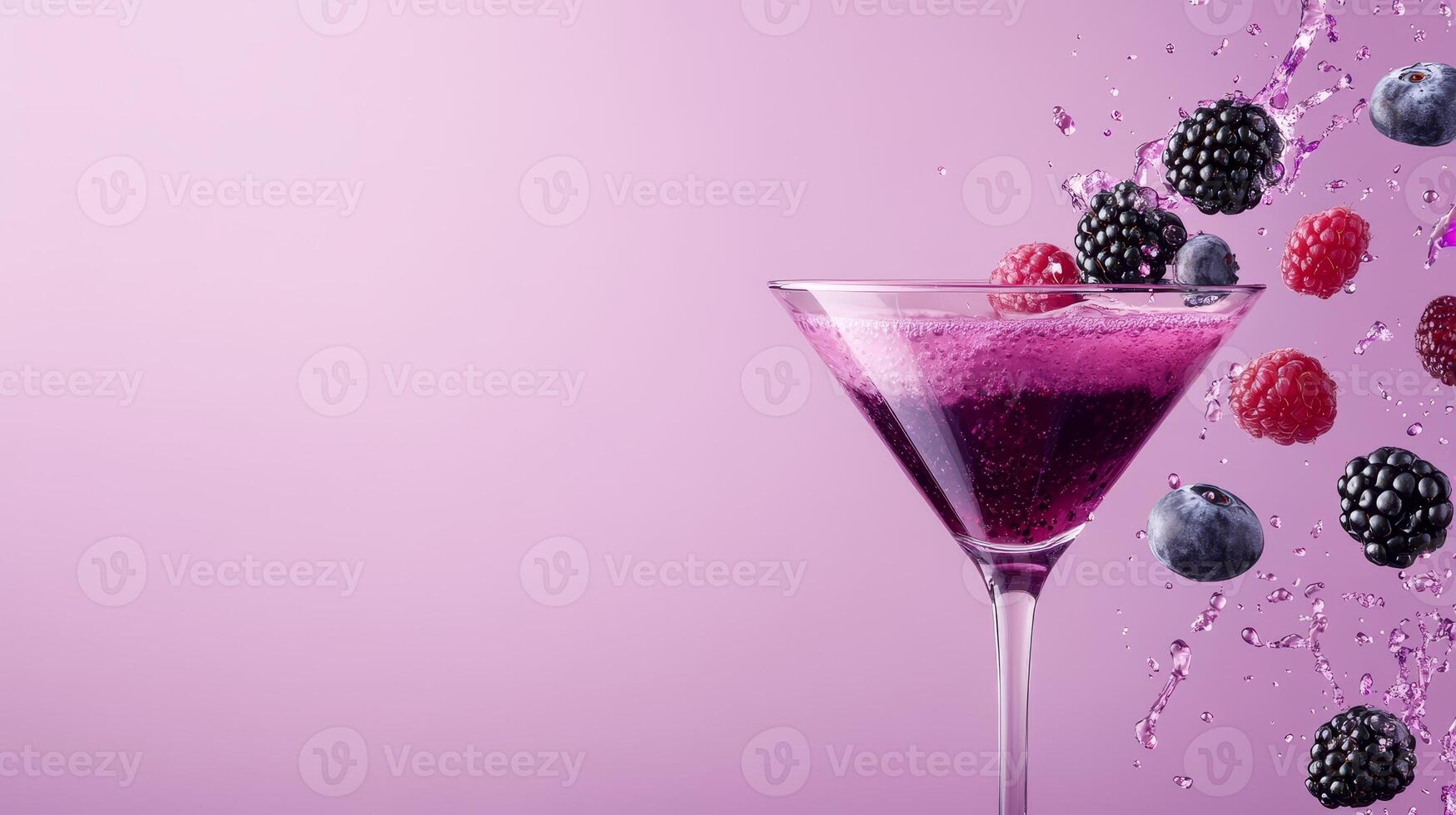 A vibrant martini glass filled with a fruity cocktail, splashing berries and droplets in an artistic display on a smooth pink backdrop photo