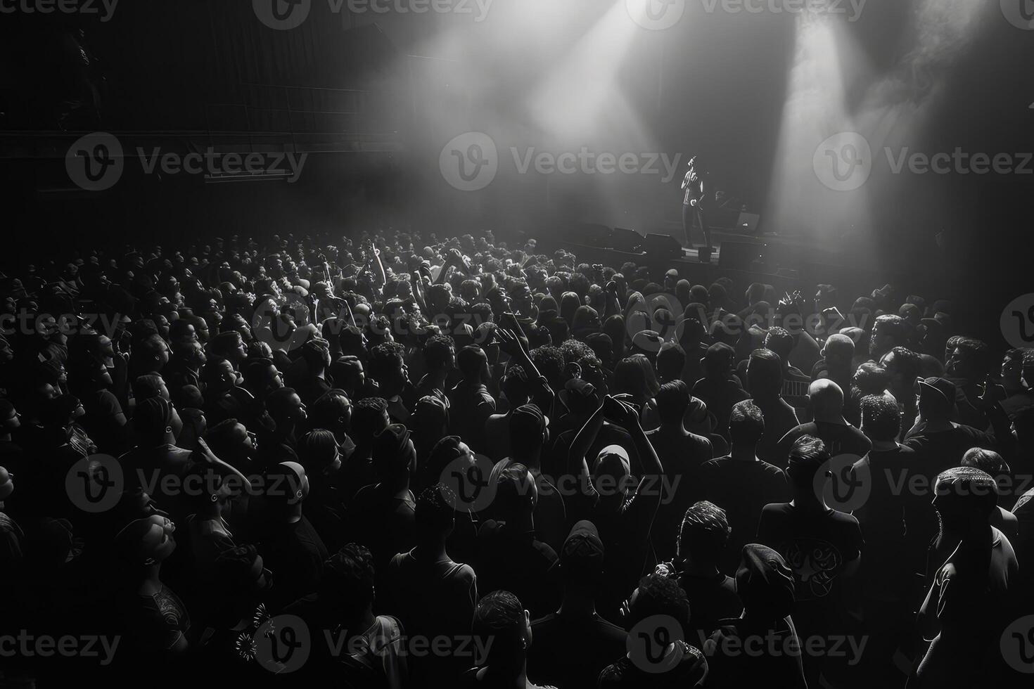 A vibrant crowd of enthusiastic fans stands closely packed in a dark concert space, eagerly anticipating the performance ahead photo