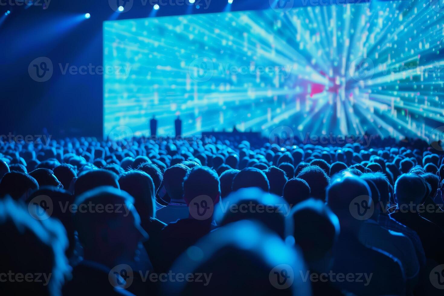 Numerous attendees are focused on a spectacular visual presentation at a lively event in a large venue photo