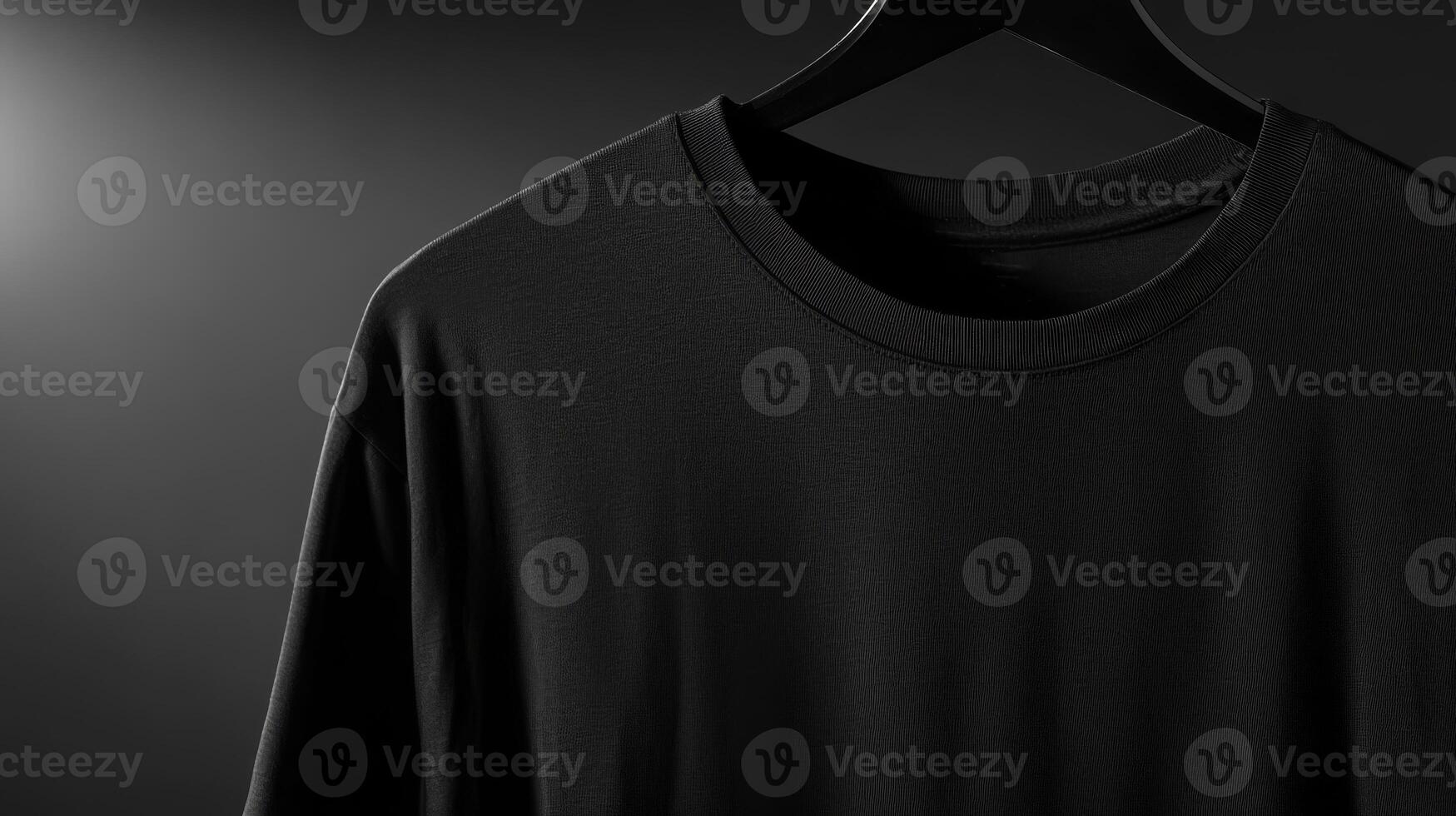 A simple black t-shirt is displayed on a hanger, illuminated by soft, dramatic lighting that accentuates its fabric texture and design photo