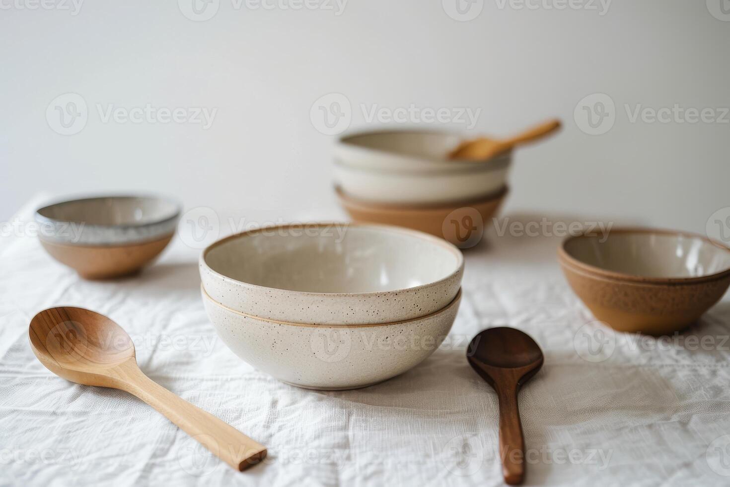Beautifully crafted ceramic bowls of various sizes and colors displayed alongside wooden spoons photo