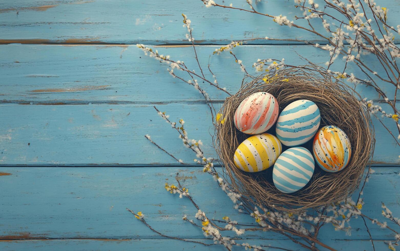 Decorative Colorful Eggs in Bird Nest on Blue Wood Background with Blooming Tree Branch photo