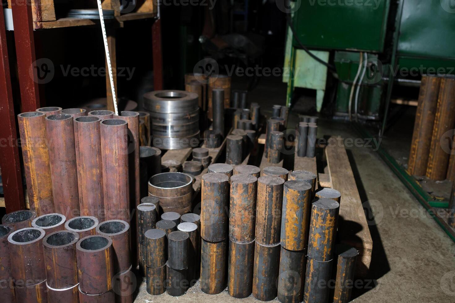 Various metal cylinders and pipes stacked in a workshop setting during daytime in a manufacturing facility photo