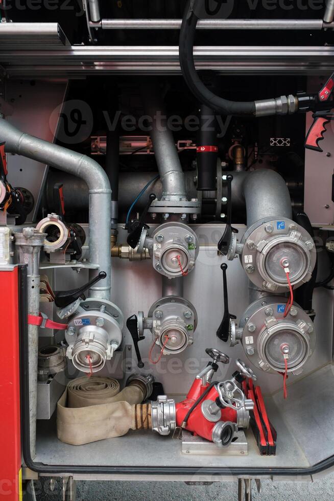 Fire engine equipment showcasing hoses, valves, and nozzles inside a fire truck during a firefighting demonstration in an urban area photo