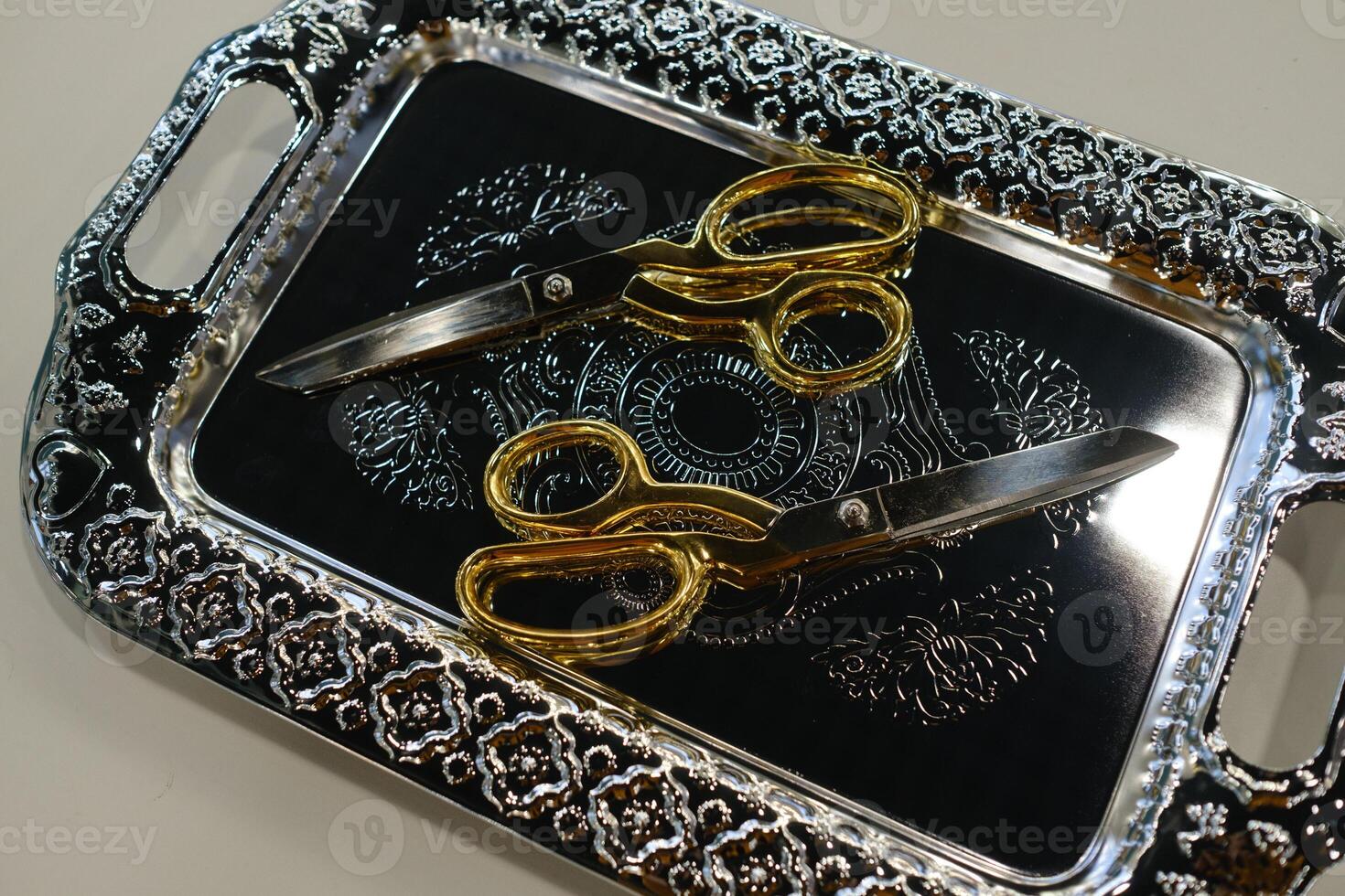 Golden scissors and ornate silver tray displayed elegantly on a surface in a bright room for a creative event photo