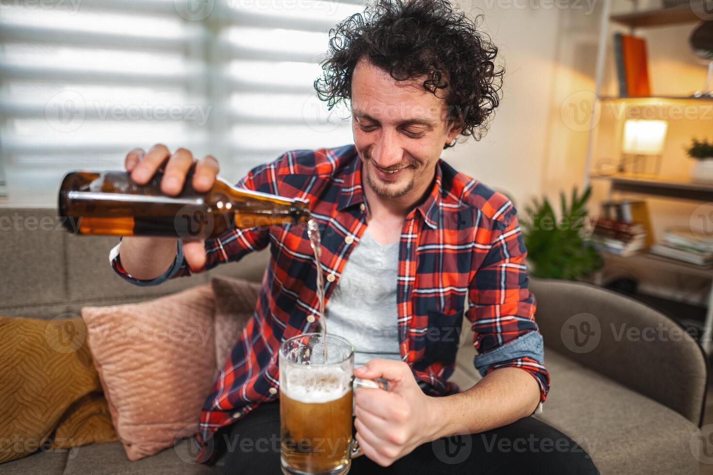Young man pouring beer into glass at home photo