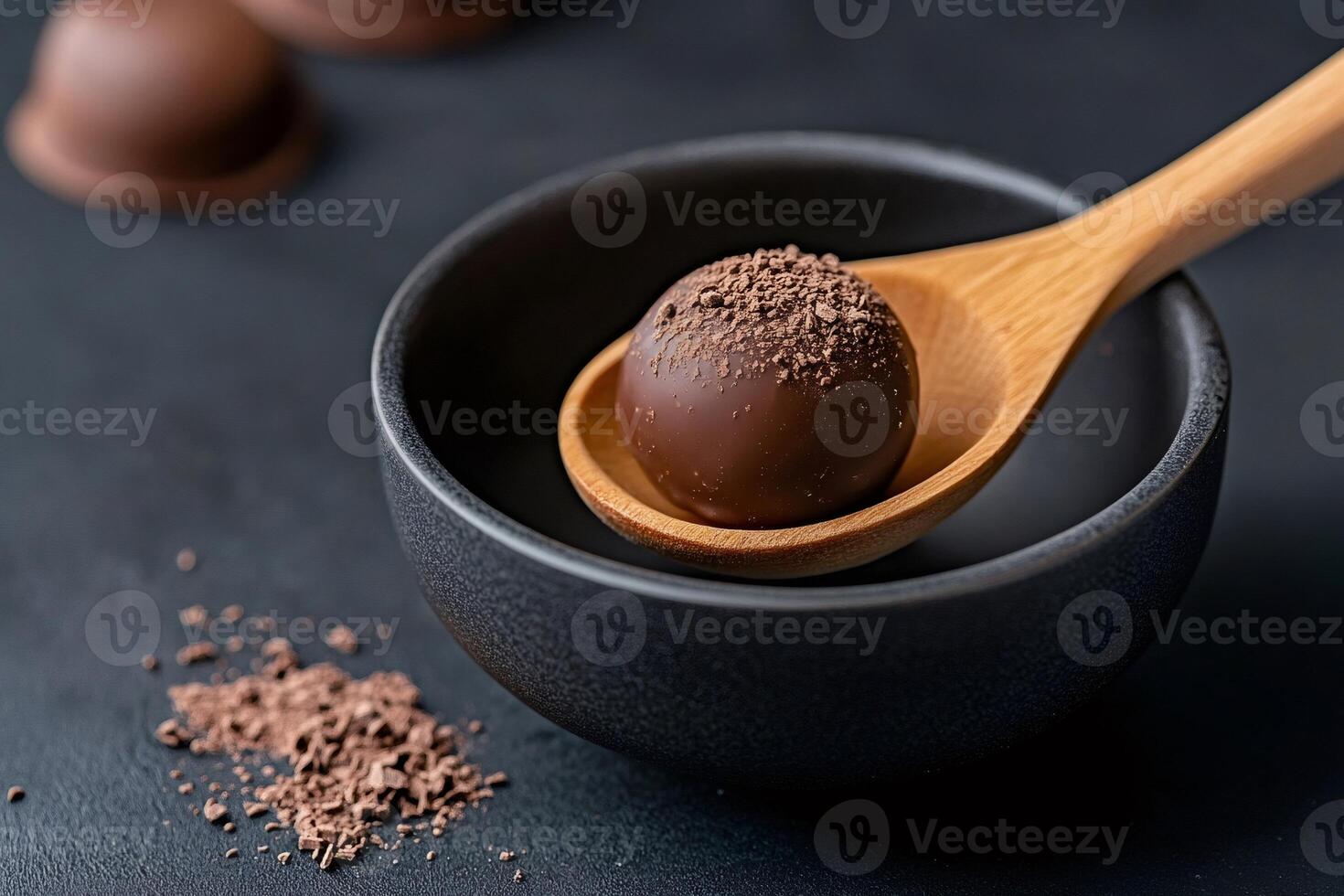 Chocolate truffle with cocoa powder topping resting on wooden spoon over dark bowl photo